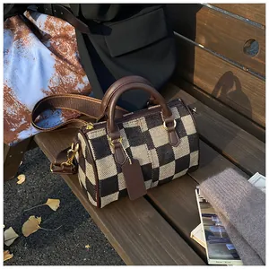 Detail of checkered canvas Boston bag with brown leather handles and wide shoulder strap