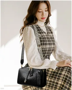 Detail of black crocodile texture leather bag featuring stylish wide woven shoulder strap