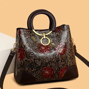 Vintage embossed floral leather handbag with brown handles and a gold hexagonal charm