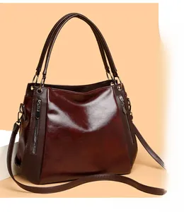 Detailed view of deep red soft leather tote bag showing glossy texture and metal zippers