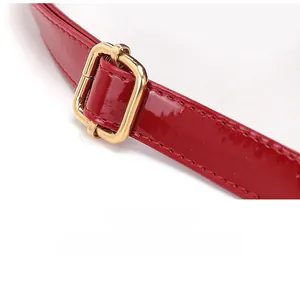 Dettaglio della tracolla in pelle verniciata rossa con fibbia dorata regolabile