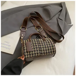 Detailed macro view of the houndstooth fabric texture and brown faux leather handle
