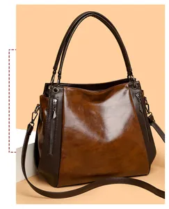 Detail view of the vintage soft leather tote showing dark brown handles and side zippers