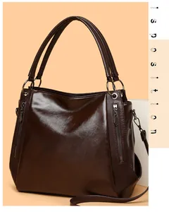 Detail of dark brown leather tote bag with decorative zippers and metallic hardware