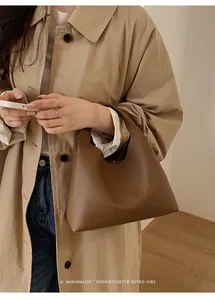 Detalle de la textura de cuero granulado marrón en un bolso tipo cubo minimalista de mujer