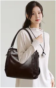 Detail of dark brown faux leather tote with glossy finish and metal zipper accents