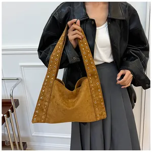Détail du sac bandoulière en daim marron avec des rivets dorés sur la large sangle