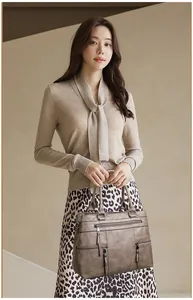 Detail view of the brown leather texture and multiple zipper pockets on this shoulder bag