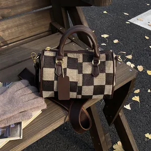 Classic checkered canvas Boston bag with brown leather handles on autumn bench