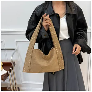 Détail du sac bandoulière en daim avec rivets dorés porté par un mannequin en cuir noir