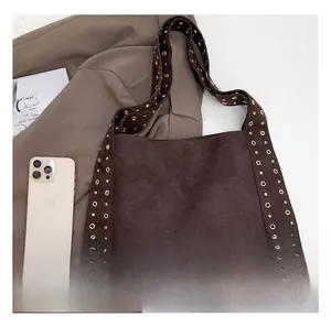 Détail du cabas en daim marron foncé avec rivets dorés et comparaison de taille de smartphone