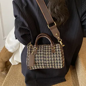 Fashionable houndstooth boston handbag with brown leather trim and wide shoulder strap