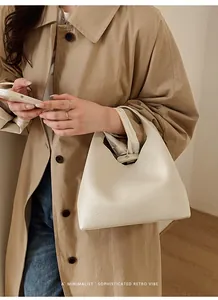 Bolso tipo cubo de cuero blanco con textura lichi combinado con una gabardina color caqui
