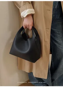 Detalle del bolso tipo cubo en cuero negro con una estética retro y minimalista