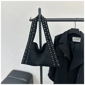 Détail du sac bandoulière en daim noir avec œillets métalliques dorés sur la bandoulière