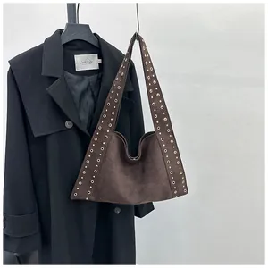 Détail du sac Hobo en daim marron foncé avec rivets métalliques dorés et large bandoulière