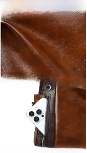 Detail of dark brown lychee texture leather and functional front vertical zipper pocket