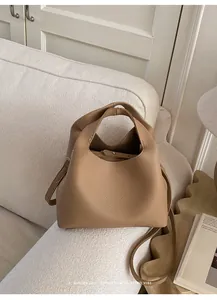 Primer plano del bolso cubo de cuero granulado caramelo en un sofá minimalista