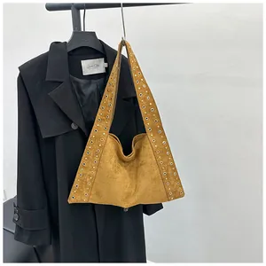 Détail d'un sac hobo en daim marron avec œillets métalliques et une grande capacité