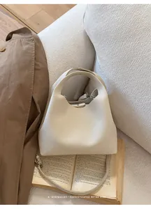 Primer plano detallado de un bolso tipo cubo de cuero granulado en blanco crema