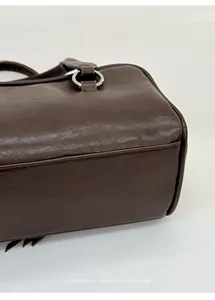 Detail of silver ring buckles and stitching on a dark brown leather shoulder bag