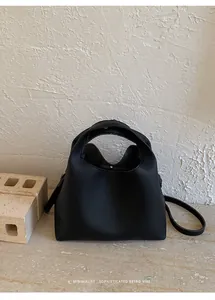 Detalle de bolso cubo de cuero negro con textura de guijarros y asas laterales retro