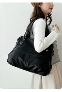 Detail of black tote bag showing soft lychee texture and silver metal rivets on strap