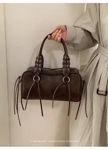 Detail shot of a retro dark coffee shoulder bag featuring long tassels and silver eyelets