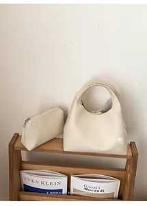 Detalle del bolso de hombro en cuero granulado crema con neceser a juego incluido