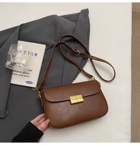 Close-up of vintage dark brown matte leather crossbody bag with golden metal buckle