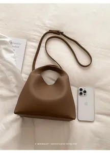 Detalle del bolso tipo cubo de cuero granulado marrón con hebilla plateada fina