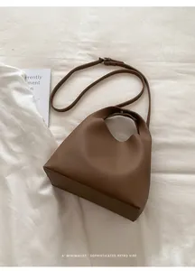 Vista superior de bolso tipo cubo de cuero marrón sobre fondo de tela minimalista