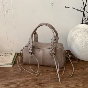 Khaki Boston shoulder bag with rivet studs and woven tassel details on wooden table