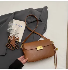 Retro brown leather crossbody bag with gold buckle and adjustable strap on neutral background