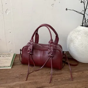 Vintage burgundy cylindrical shoulder bag with stylish tassel accents and metal hardware