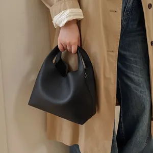 Bolso cubo minimalista de cuero negro con textura de guijarros en una modelo femenina