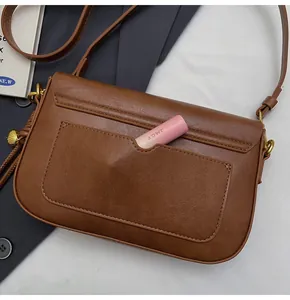 Detailed close-up of the brown leather crossbody bag back pocket with a lipstick inside