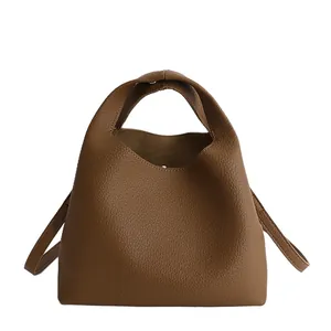 Bolso tipo cubo de cuero marrón con grano de lichi, asa minimalista y una textura muy suave