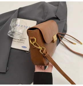 Close-up of retro brown crossbody bag with gold square buckle and leather strap details