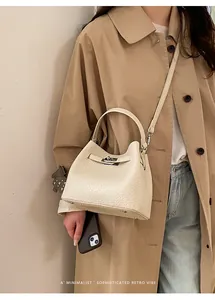 Detalle de bolso saco crema con textura de lichi y cierre de metal plateado giratorio