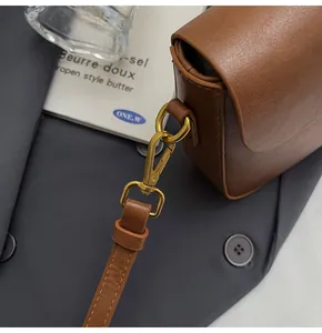 Detailed close-up of brown vintage square bag with elegant gold metal buckle hardware