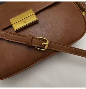 Detail of caramel faux leather bag featuring lychee texture and gold metal buckle closure