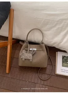 Detalle de bolso tipo cubo de cuero gris con cierre de plata y colgante de caballito