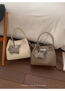 Detalle de bolsos tipo cubo en piel texturizada con herrajes plateados y adornos colgantes