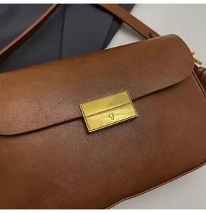 Close-up of a vintage brown leather shoulder bag featuring a refined gold metal buckle