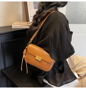 Side view of a vintage brown leather shoulder bag with gold clasp and woven strap knots