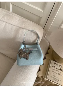 Detalle de bolso cubo azul claro con textura de cocodrilo y colgante de caballo retro