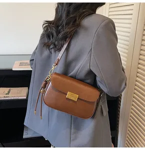 Detail of vintage brown leather box bag featuring gold buckle and knotted strap