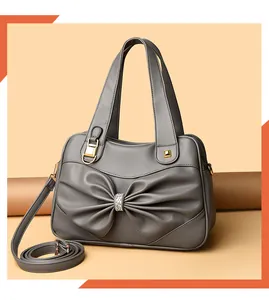 Close-up of a charcoal grey handbag featuring a pleated bow and rhinestone buckle detail