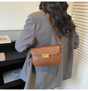 Brown vintage leather shoulder bag with gold clasp and tassel on a female model